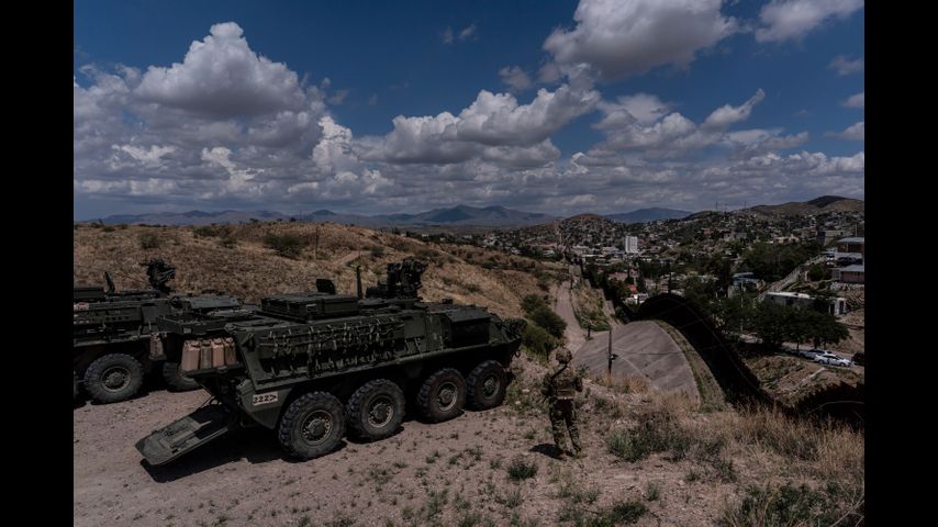 A man is halted climbing the US-Mexico border wall. Under new Trump rules, US troops sound the alarm