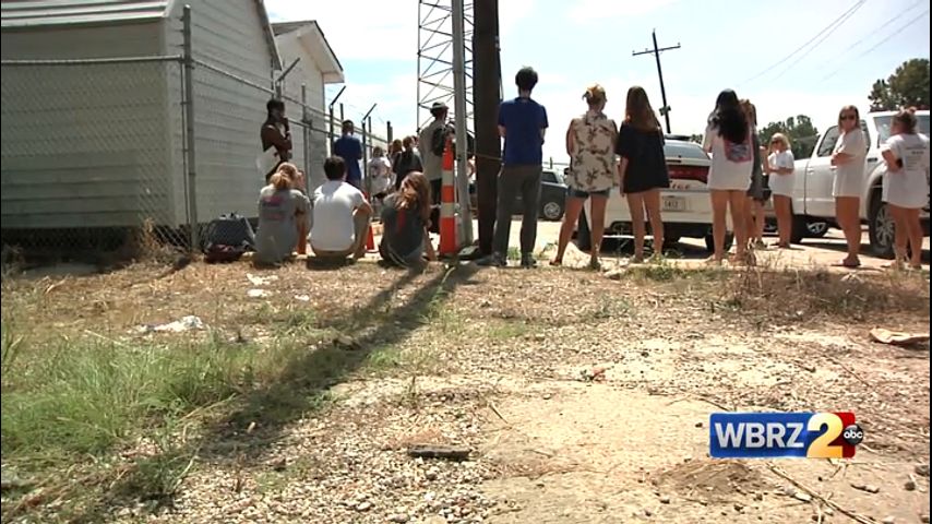 LSU students and fans stand in the heat for their cars that were towed ...